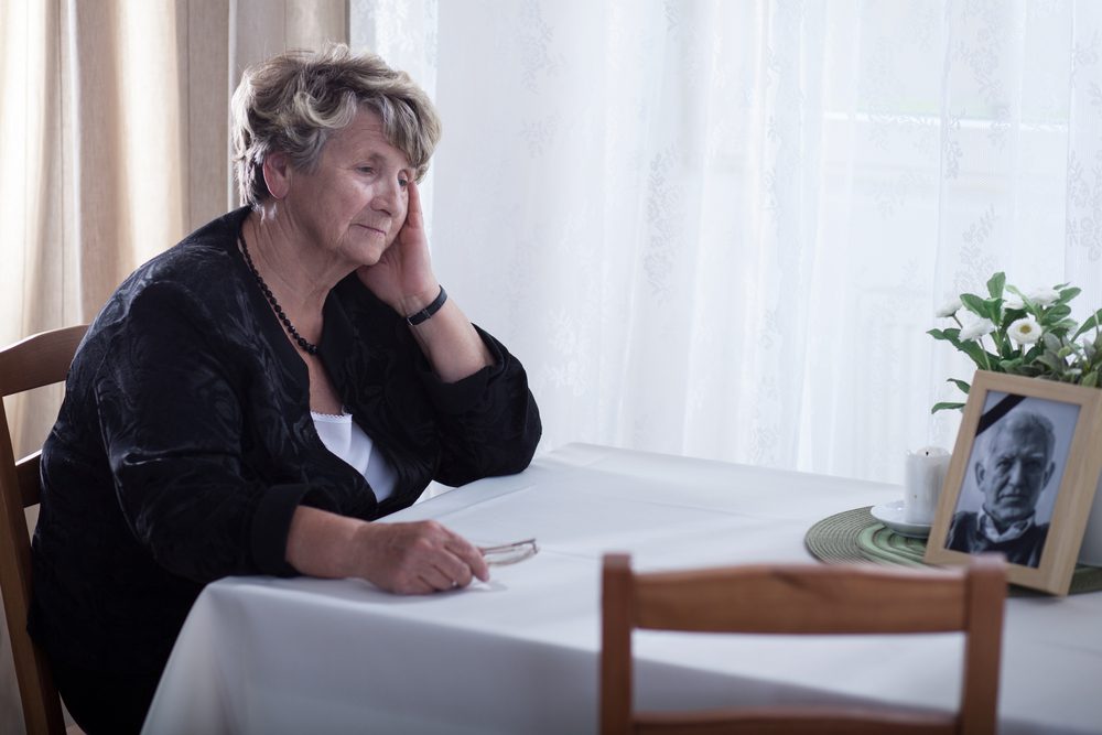 Grieving lady at a table with a photo of a recently deceased loved one