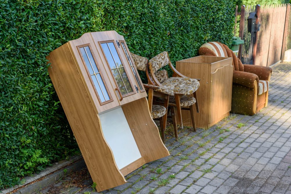 furniture placed outside by a bush after a house clearance